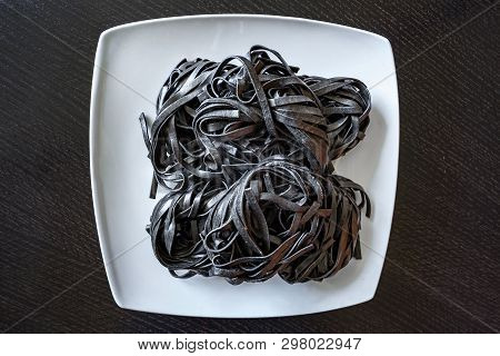 Dry Black Pasta With Cuttlefish Ink. Pasta Of Durum Wheat Semolina With Squid Ink On A Square Plate