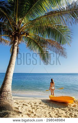 Young Woman In Bikini Standing On A Sandy Beach With Sea Kayak And Paddle, Nacula Island, Fiji