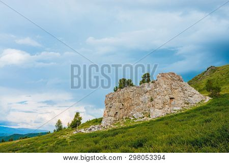 Landscape With Big Rocky Stone On Hill In Highland Under Cloudy Sky. Rock On Mountainside With Conif