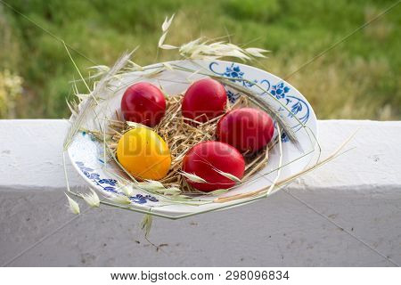 Easter Red And Yellow Eggs With Hay In The Plate On Balkony