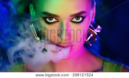 Fashion Girl Smoking E-cigarette In Colourful Neon Lights