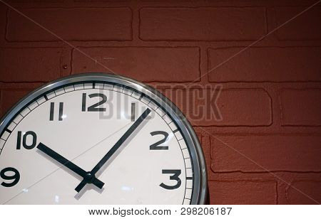 Classic Round Clock With A White Dial On The Background Of A Brown Brick Wall. Time Does Not Wait.