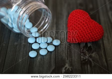 Blue Pills And Red Knitted Heart On Dark Wooden Table. Concept For Antidepressants, Hypertension, Bl