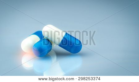 Blue And White Capsule Pills On Gradient Background. Global Healthcare Concept. Antibiotics Drug Res