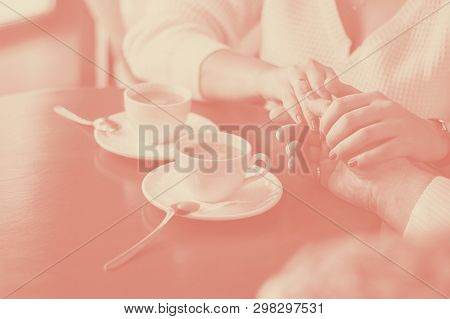 Man And Woman Hold Hands, Close Up Of Couples Arms On Red Wooden Table In Restaurant With Two White 