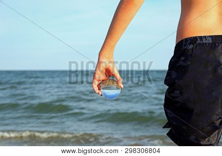 Young Boy With Crystal Glass On The Hand And The Ocean On Background