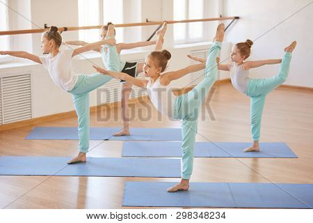Ull Length Portrait Of Group Of Girls Doing Yoga Poses On Mats In Studio, Copy Space