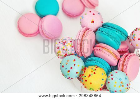 Colorful Sweet Macaroons And Cake Pops In Bowl On Wooden White Background With Copy Space. Food For 