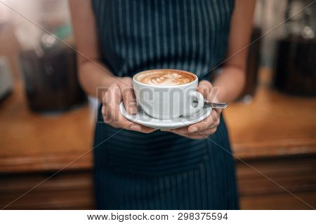 Close Up Of A Waitress Holding A Well Poured Coffeecropped Close Up Of Female Serving Coffee With La
