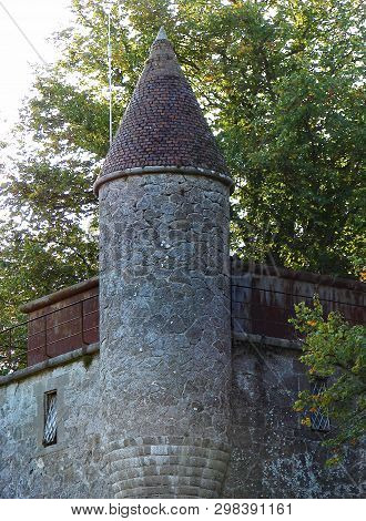 Old Tower With Conus Roof Between Green Branches