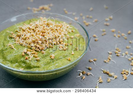 Refreshing Green Smoothie In Glass Bowl With Green Buckwheat Sprouts On Grey Background. Raw Dish. C