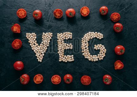 Top View Of Red Ripe Tomatoes In Form Of Frame And Letter Shaped Chickpeas On Dark Background. Vegan