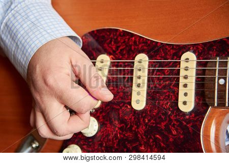 A Man Plays The Electric Guitar With A Mediator, Close-up