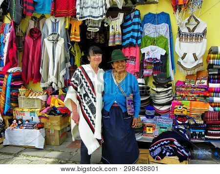 Alausi, Ecuador - February 18, 2015: Native Ecuadorian Woman-trader With Tourist Woman Next The Disp