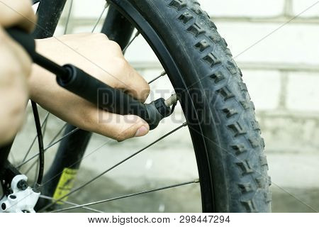 Hand Pump. Guy Shakes A Flat Tire From A Mountain Bike. Bicycle Wheel Close-up