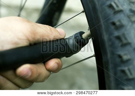 Hand Pump. Guy Shakes A Flat Tire From A Mountain Bike. Bicycle Wheel Close-up
