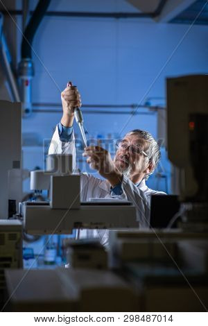Senior scientist in a chemistry lab carrying out research - looking at gas chromatography samples, preparing the analysis on a modern gas chromatographer (color toned image)