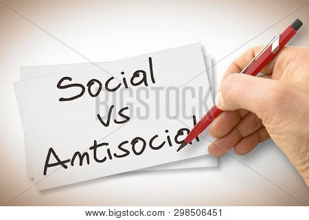 Hand Writing Social Vs Antisocial With A Pencil On A Blank Sheet - Concept Image