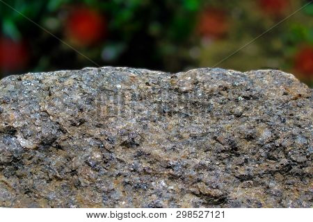 Rock Or Stone On Blurred Bokeh Background With Red Spots. Granite Crouan Rim Or Pick Edge Like Cliff