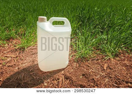 Blank Pesticide Jug Container Mock Up In Wheatgrass Field. Using Chemical In Crop Protection Agricul