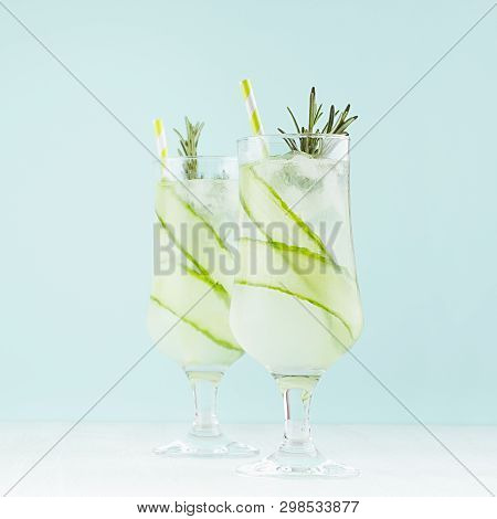 Detox Refreshing Drinks - Cucumber Water In Wineglasses With Ice Cubes, Straw, Rosemary, Lime On Pas