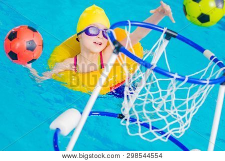 Swimming Pool Fun Time. Caucasian Nine Years Old Girl Playing Ball Inside The Pool.