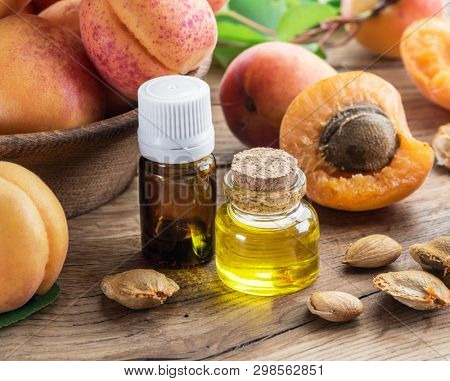 Apricot kernel oil and apricot kernels on wooden background.