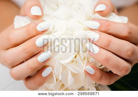 Closeup of hands of a young woman with white nails after manicure