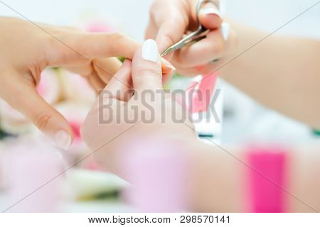 Woman having her finger nails cut during manicure with scissors 
