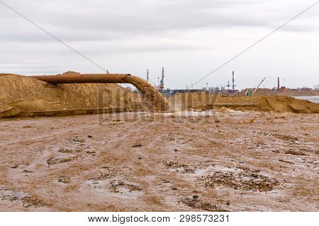 Rusty Pipe On The River Bank, From Which Sewage Flows, Dirty Sand Slurry