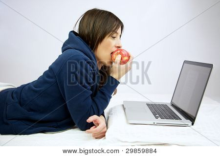 여 자가 웃 고 먹고 침대에 누워 컴퓨터 앞에서 애플