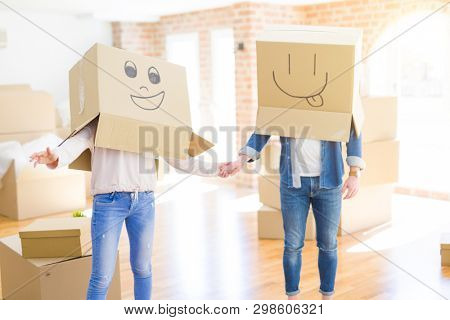 Couple having fun at new apartment wearing boxes with funny faces over head