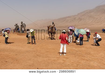 Flaming Mountains, Xinjiang, China - August 12, 2012: Group Of Chinese Tourists Taking Pictures Near