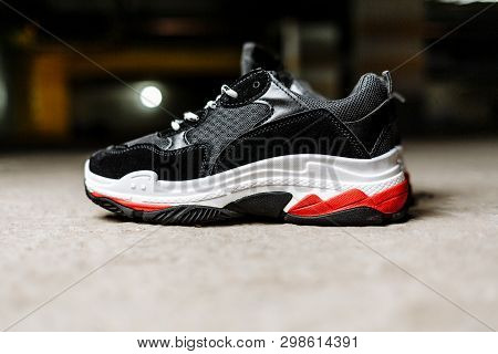 Black Sneaker On Thick White With Red Accents Soles On A Gray Concrete Background