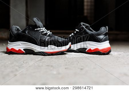 Black Sneakers On Thick White With Red Accents Soles On A Gray Concrete Background