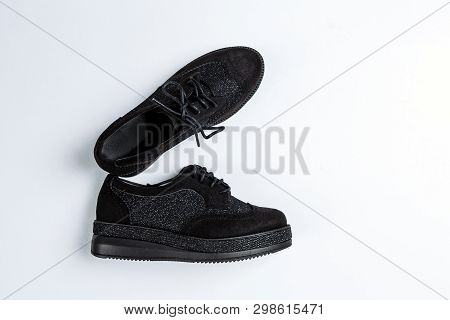 A Pair Of Black Shoes With Shiny Inserts On Thick Soles On A White Background