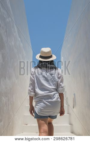Asian Woman Wear White Shirt And Weave Hat Walking Up On Concrete Stairs In Daylight.