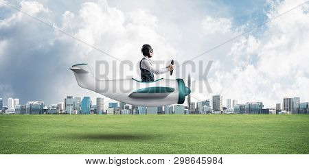 Young Aviator Driving Small Propeller Plane. Modern Metropolis With High Buildings On Background. Ma