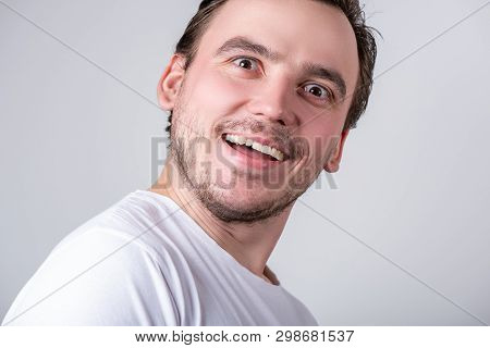Handsome Brunette Guy With Bristles In A White T-shirt Makes Funny Grimaces On His Face