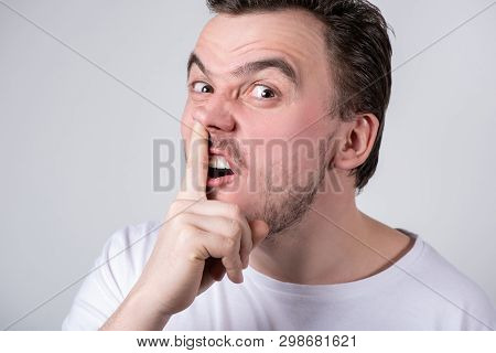 Handsome Brunette Guy With Bristles In A White T-shirt Picks His Finger In His Nose