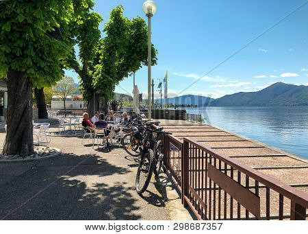 Luino, Lombardy, Italy - April 30, 2019: People Resting At The Outdoor Bar On The Lakefront Of Luino