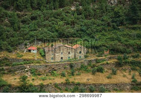 Hilly Landscape Covered By Trees And Terraced Fields With A Rustic Country House Near Alvoco Da Serr