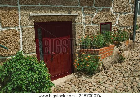 Facade Of Cute Stone House With A Wooden Door And Flowers, On A Cobblestone Alley At Alvoco Da Serra