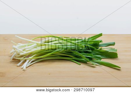 Raw Green Garlic On Cutting Board Preparated For Cooking. Close-up Photo With Selective Focus.
