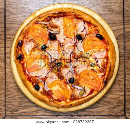 pizza with ham and tomatoes on the wooden background