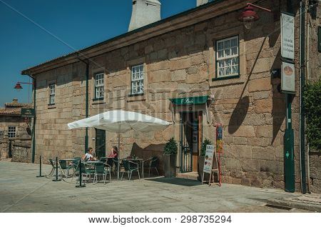 Guarda, Portugal - July 16, 2018. Two Girls Sitting In Front Of Coffee Shop In Old Stone Building At