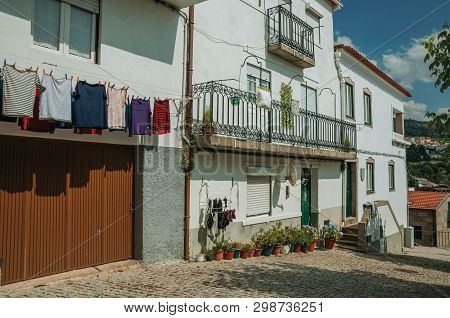 Gouveia, Portugal - July 17, 2018. Colorful Clothes Hung To Dry In Front Of Building With Whitewashe