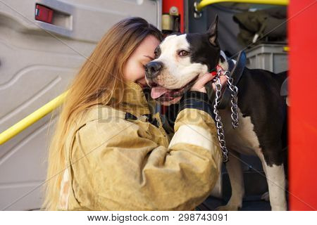 Image of firewoman with dog standing near fire truck at station
