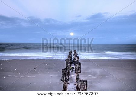 Moonset At Dawn Over A Dilapidated Pier On The Beach In Port Royal