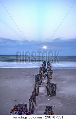 Moonset At Dawn Over A Dilapidated Pier On The Beach In Port Royal